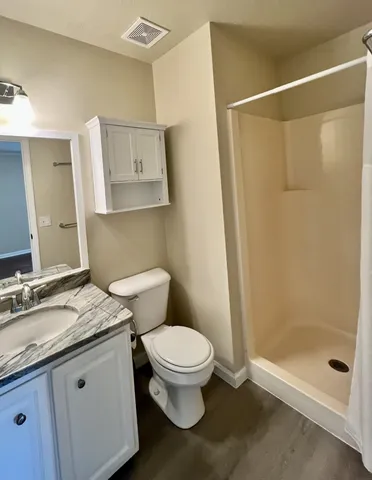 a bathroom with a granite countertop sink a toilet and a shower