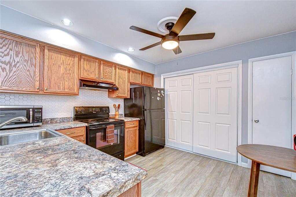 13402 Pinelake Way, Unit 202B Tampa, FL 33618 - Photo 19 of 42 a kitchen with stainless steel appliances granite countertop a stove top oven a refrigerator a sink with wooden cabinets and wooden floor
