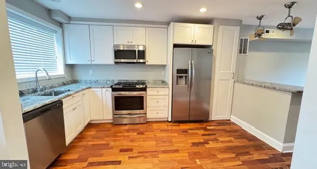 a kitchen with stainless steel appliances granite countertop a refrigerator and a stove top oven