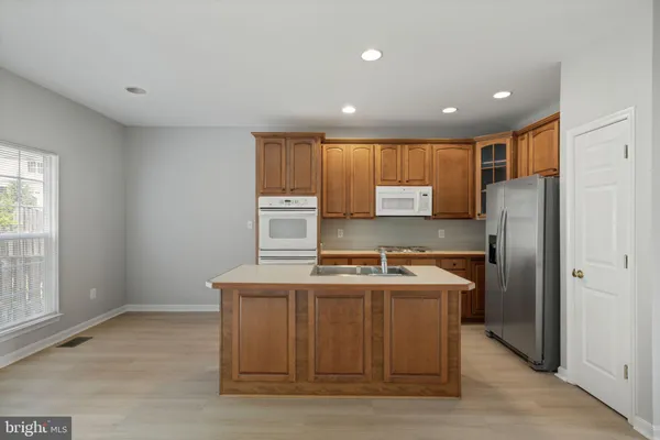 a kitchen with kitchen island stainless steel appliances a sink a stove a refrigerator a center island and a window