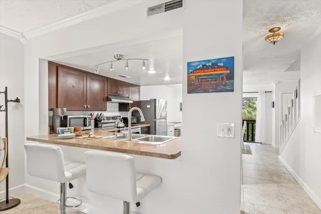 a kitchen with stainless steel appliances kitchen island granite countertop a refrigerator and a sink