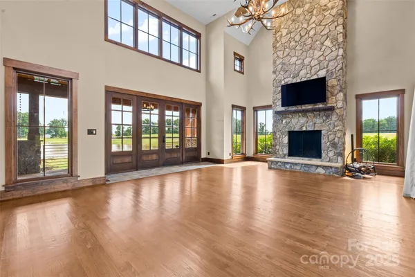 a view of an empty room with wooden floor fireplace and a window