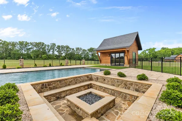a view of an outdoor space with seating swimming pool and trees in the background