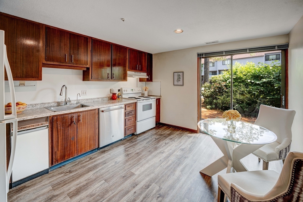 244 Old Beaverbrook, Unit 244 Acton, MA 01718 - Photo 13 of 42 a kitchen with a table chairs stove and wooden floor