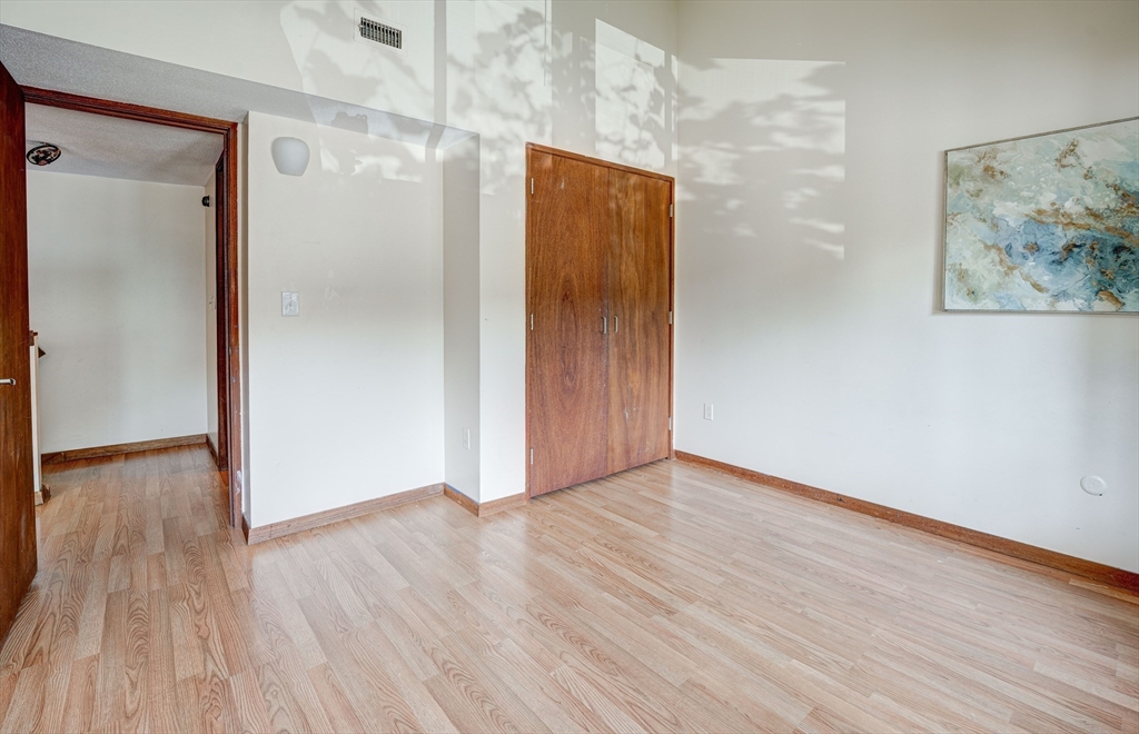 244 Old Beaverbrook, Unit 244 Acton, MA 01718 - Photo 27 of 42 a view of an empty room with wooden floor and a painting on the wall