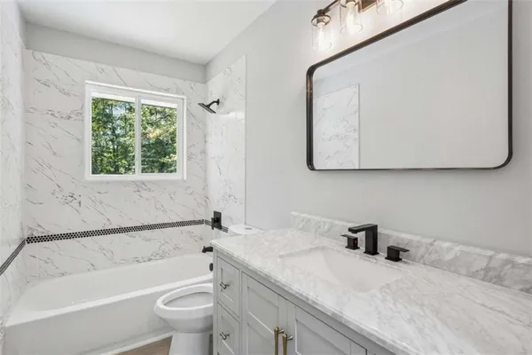 a bathroom with a granite countertop sink toilet and bathtub