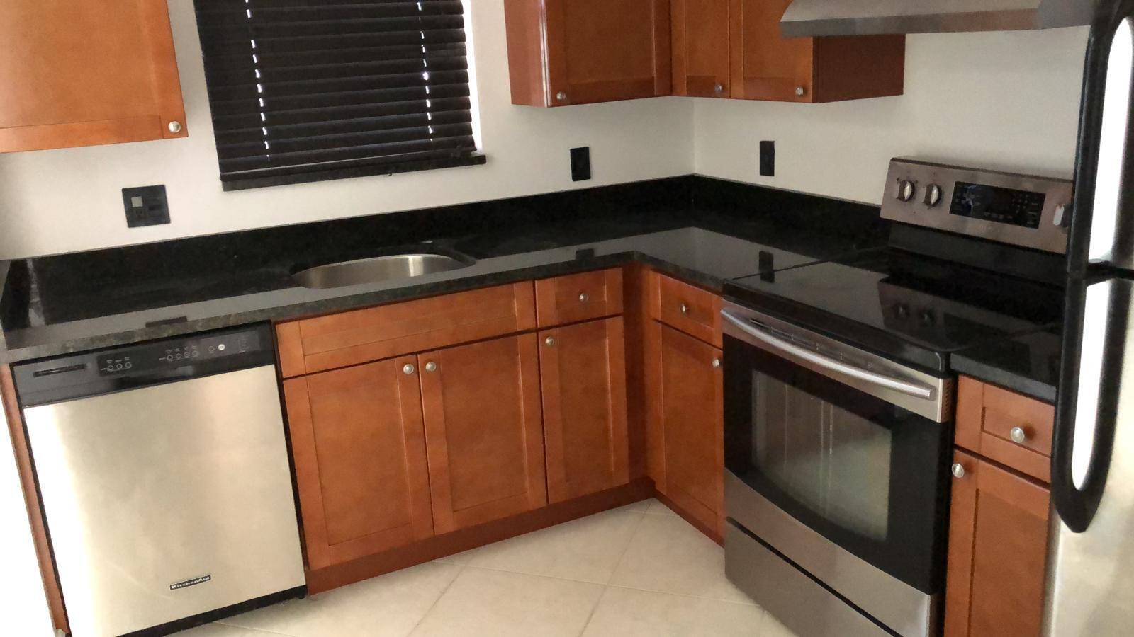 21911 Lake Forest Circle, Unit 204 Boca Raton, FL 33433 - Photo 9 of 16 a kitchen with granite countertop white cabinets and black appliances