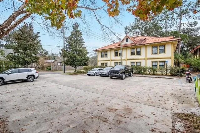 a view of a white house covered with tall trees