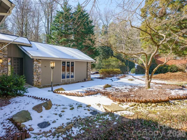 a front view of a house with a yard covered with trees