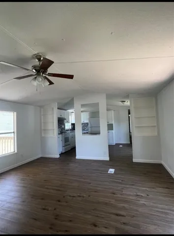 a view of empty room with wooden floor and ceiling fan