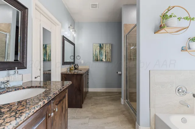 a bathroom with a granite countertop sink a mirror and a bathtub