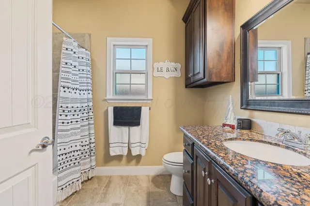 a spacious bathroom with a granite countertop toilet sink and mirror
