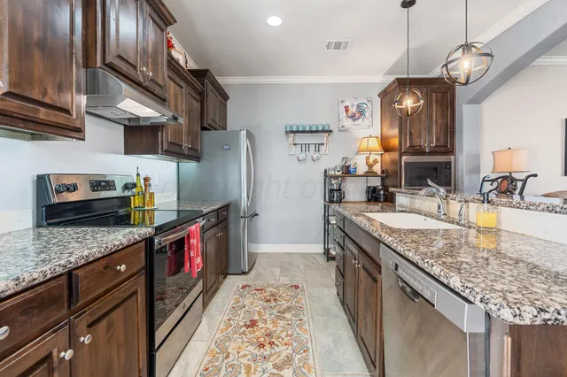 a kitchen with stainless steel appliances granite countertop a sink stove and refrigerator