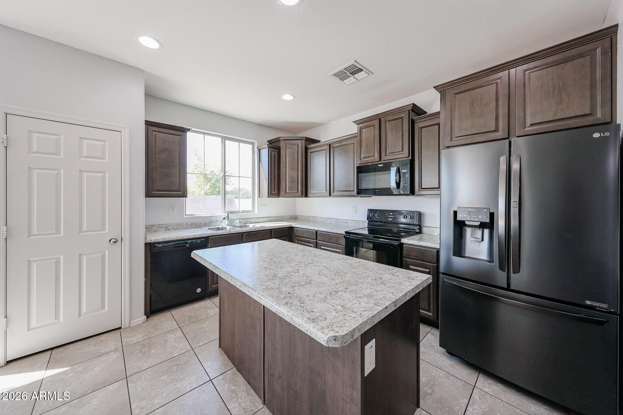 11967 West Rio Vista Lane Avondale, AZ 85323 - Photo 7 of 28 a kitchen with a refrigerator a sink and cabinets