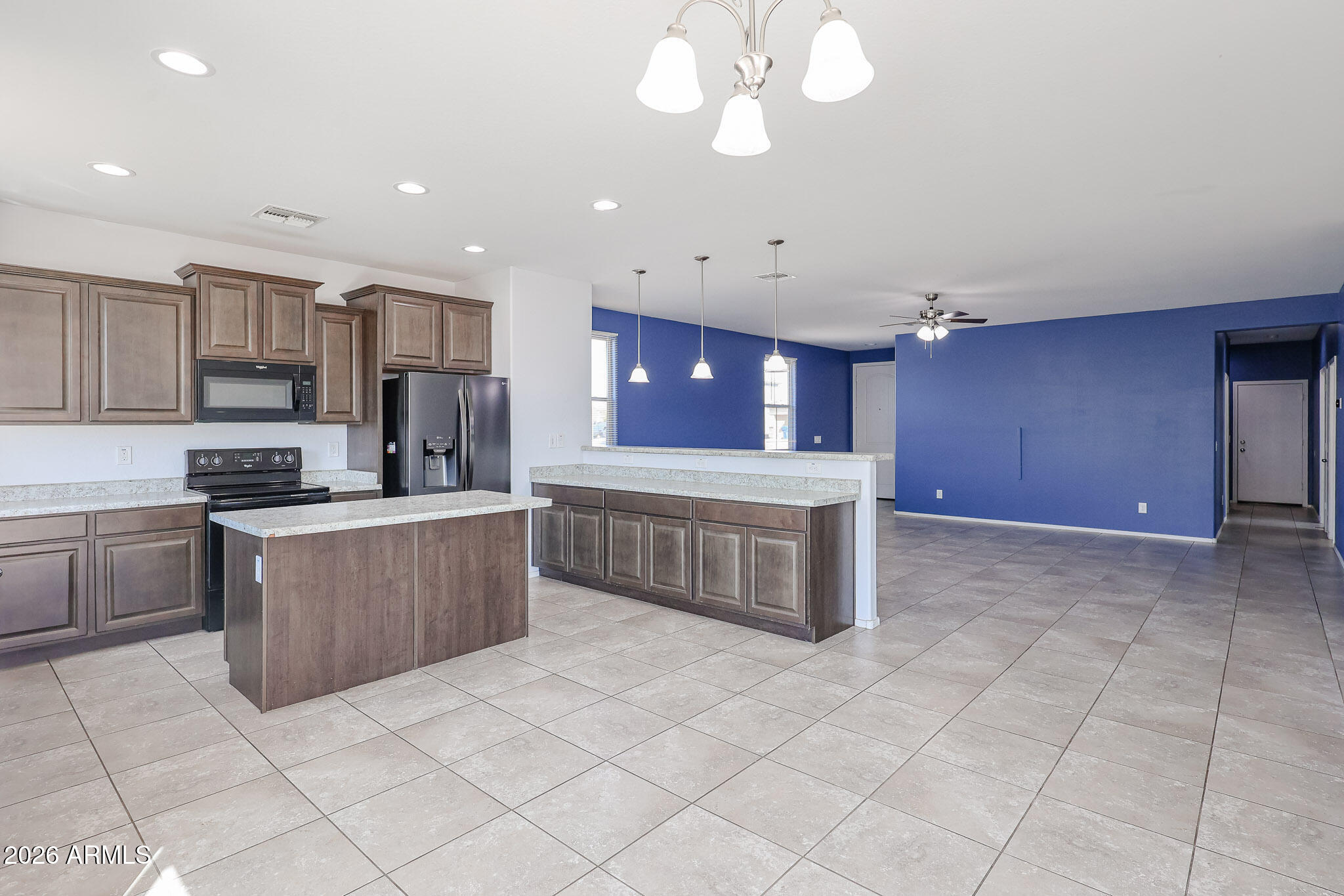 11967 West Rio Vista Lane Avondale, AZ 85323 - Photo 10 of 28 a kitchen with stainless steel appliances a sink a stove a microwave a center island and cabinets