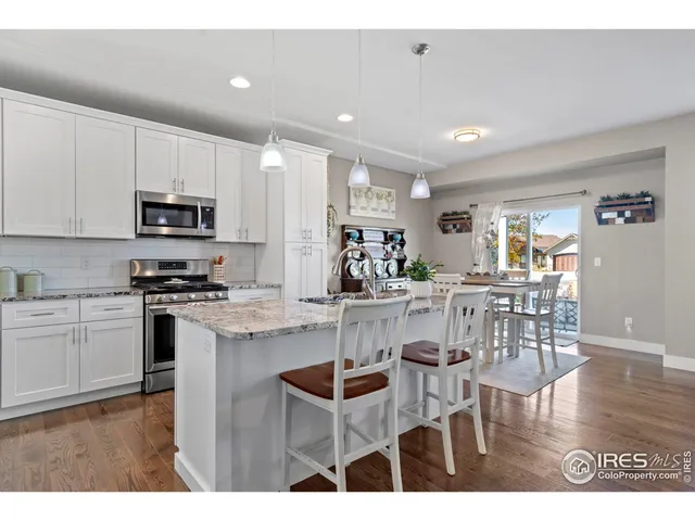 a kitchen with stainless steel appliances kitchen island granite countertop a stove a sink a microwave a dining table and chairs