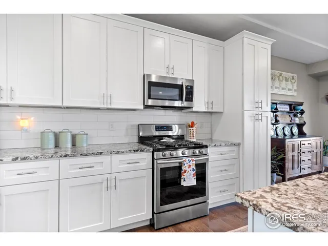 a kitchen with stainless steel appliances granite countertop a stove a sink and a white cabinets