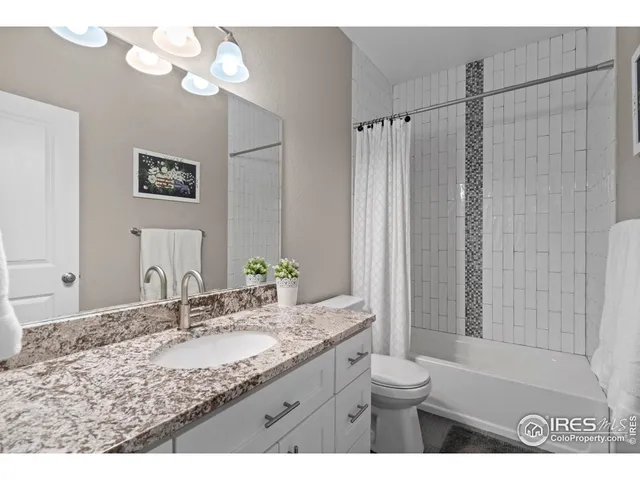 a bathroom with a granite countertop sink a toilet and a mirror