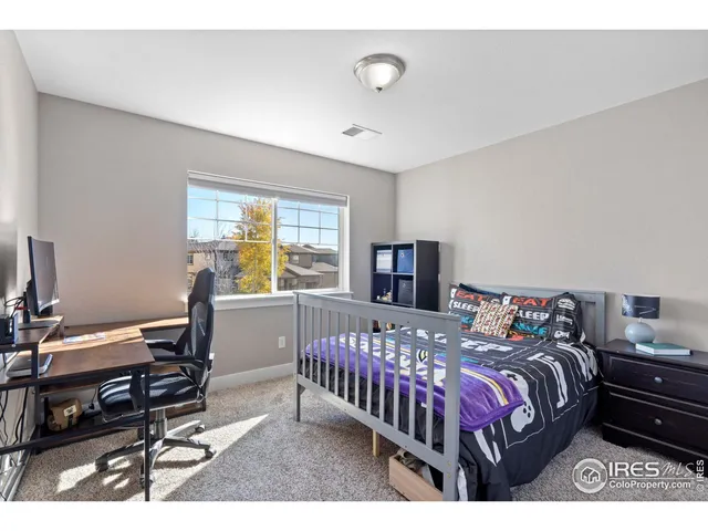 a bedroom with a bed a computer on the desk and a dresser