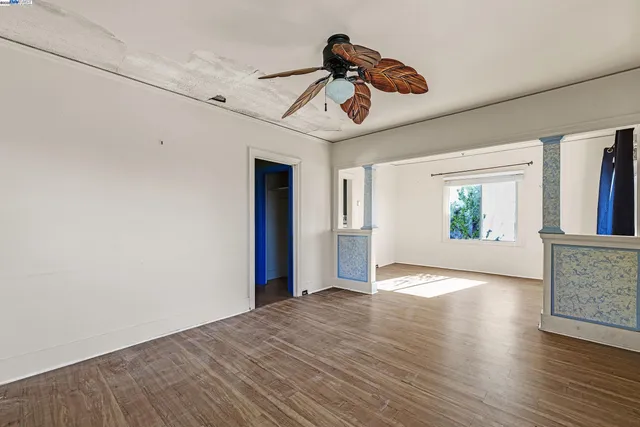a view of an empty room with window and wooden floor