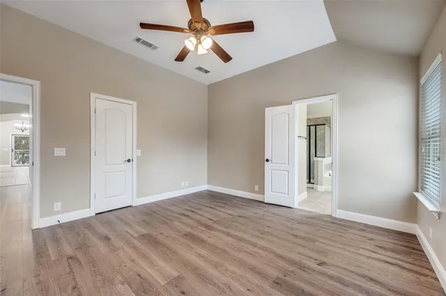 an empty room with wooden floor and a ceiling fan