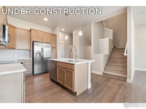 a kitchen with stainless steel appliances granite countertop a sink a stove a refrigerator and island with wooden floor