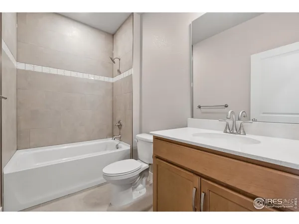 a bathroom with a granite countertop sink toilet mirror vanity and bathtub