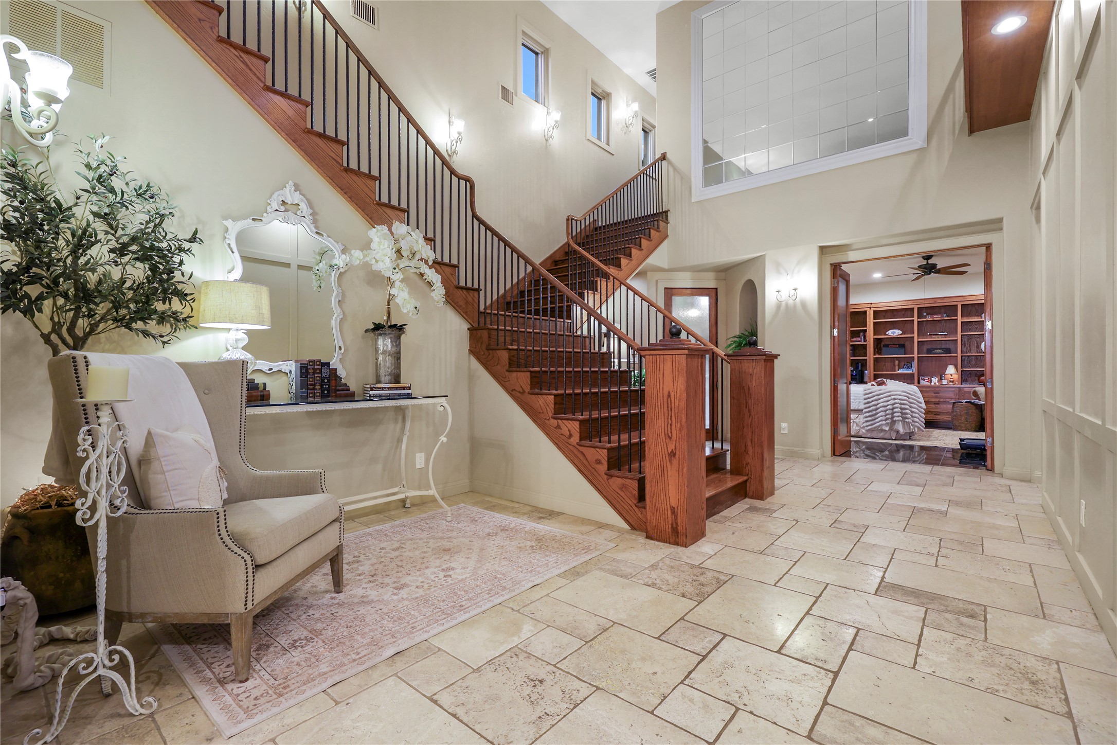 17501 Navigation Lane Lago Vista, TX 78645 - Photo 21 of 40 The property features a grand staircase with wooden treads and dark wrought iron balusters, complemented by light-colored tile flooring