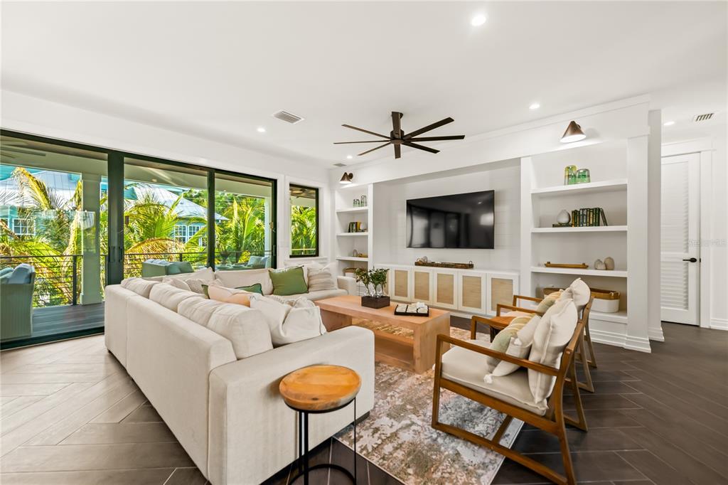 107 Maple Avenue Anna Maria, FL 34216 - Photo 22 of 68 a living room with furniture a flat screen tv and a large window