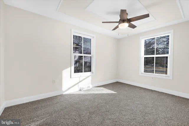 an empty room with a ceiling fan and carpet