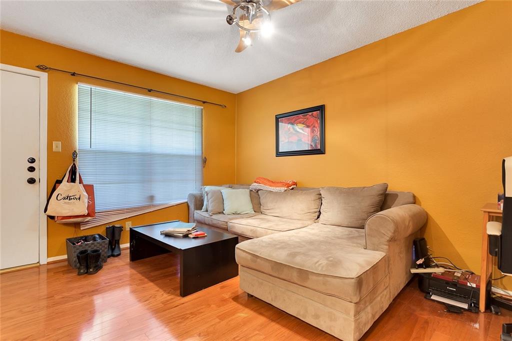 910 Duncan Lane, Unit 35 Austin, TX 78705 - Photo 3 of 20 Golden-hued walls frame a cozy living space, showcasing lustrous hardwood flooring and natural light.