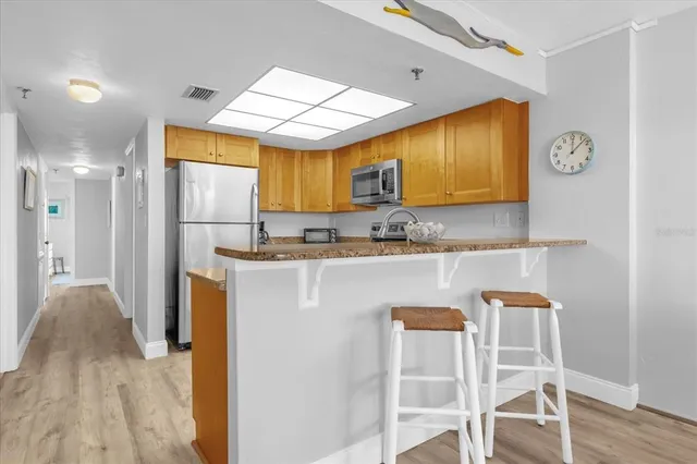 a kitchen with stainless steel appliances granite countertop a sink a stove and a wooden floor