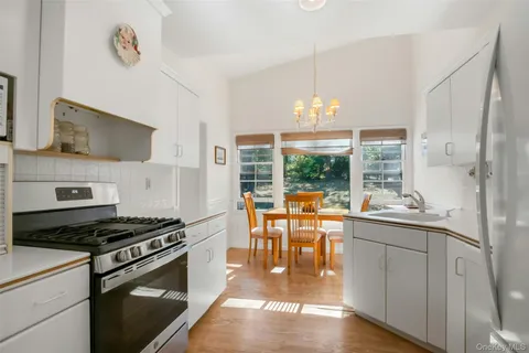 a kitchen with stainless steel appliances granite countertop a stove and a view of living room