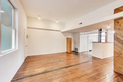 a view of empty room with wooden floor and a window