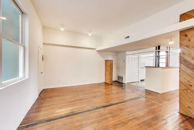 a view of empty room with wooden floor and a window