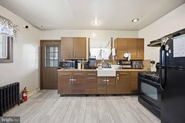 a room with kitchen island granite countertop wooden cabinets and stainless steel appliances