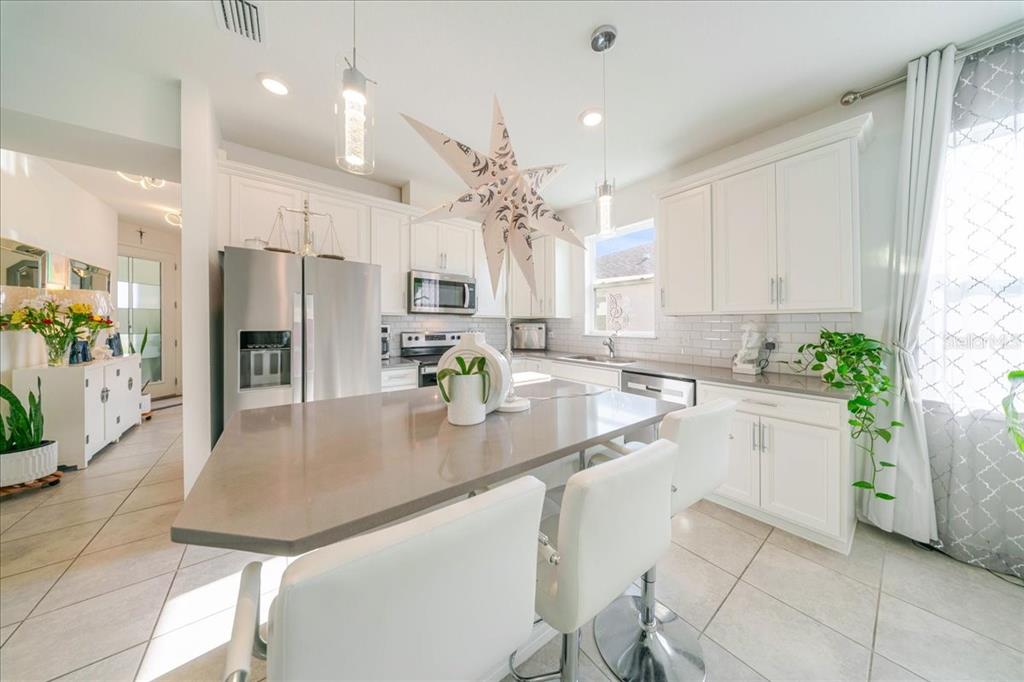 1833 Spring Shower Circle Kissimmee, FL 34744 - Photo 22 of 51 a kitchen with stainless steel appliances granite countertop a refrigerator a sink dishwasher and white cabinets with wooden floor
