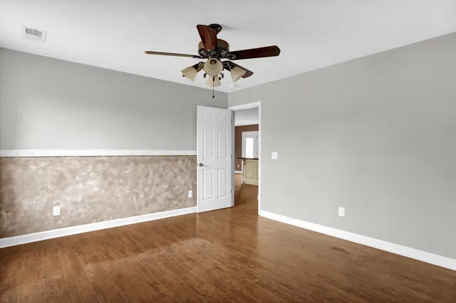 an empty room with wooden floor and windows with curtains