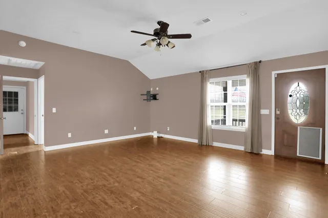 a view of an empty room with a window and wooden floor