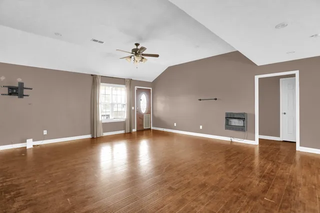a view of an empty room with window and wooden floor