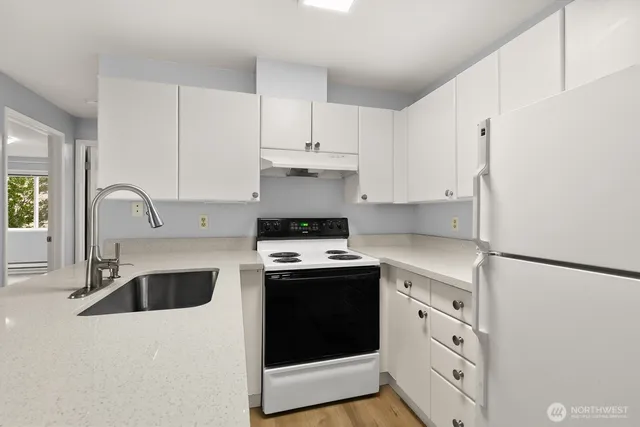a kitchen with a white refrigerator a sink and cabinets