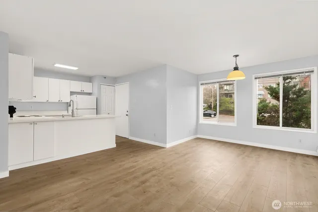 a view of kitchen and empty room with wooden floor