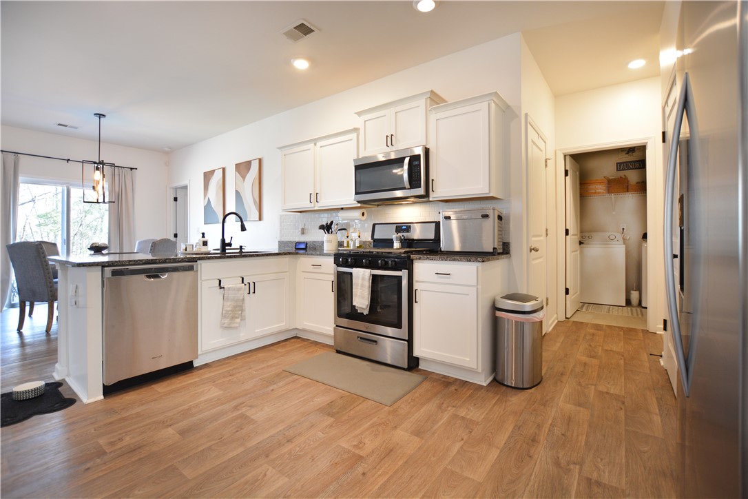 242 Hillendale Way Pelzer, SC 29669 - Photo 8 of 19 This modern kitchen features stainless steel appliances, ample counter space, and a dedicated laundry area.