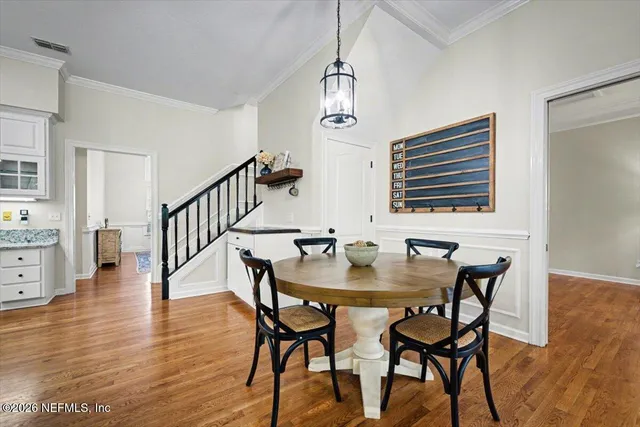 a kitchen with stainless steel appliances granite countertop a stove top oven a refrigerator a sink and white cabinets with wooden floor