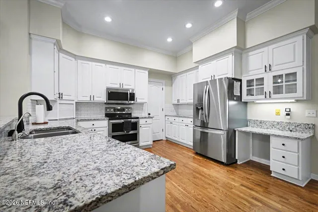 a kitchen with stainless steel appliances granite countertop a stove a sink dishwasher a refrigerator and a oven with wooden floor