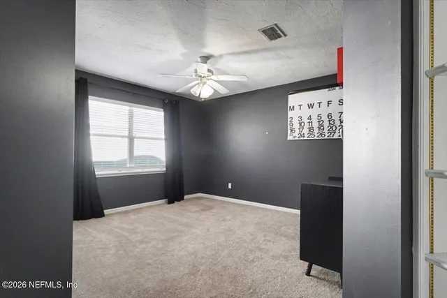 an empty room with a window and a fan