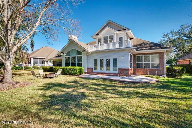 a white house with a big yard plants and large trees