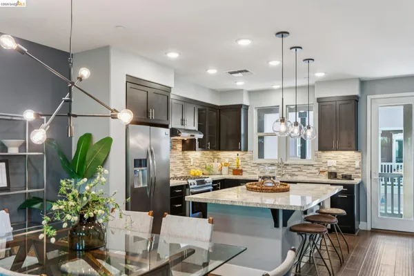 a kitchen with stainless steel appliances granite countertop a kitchen island a stove a refrigerator a oven a sink and chairs