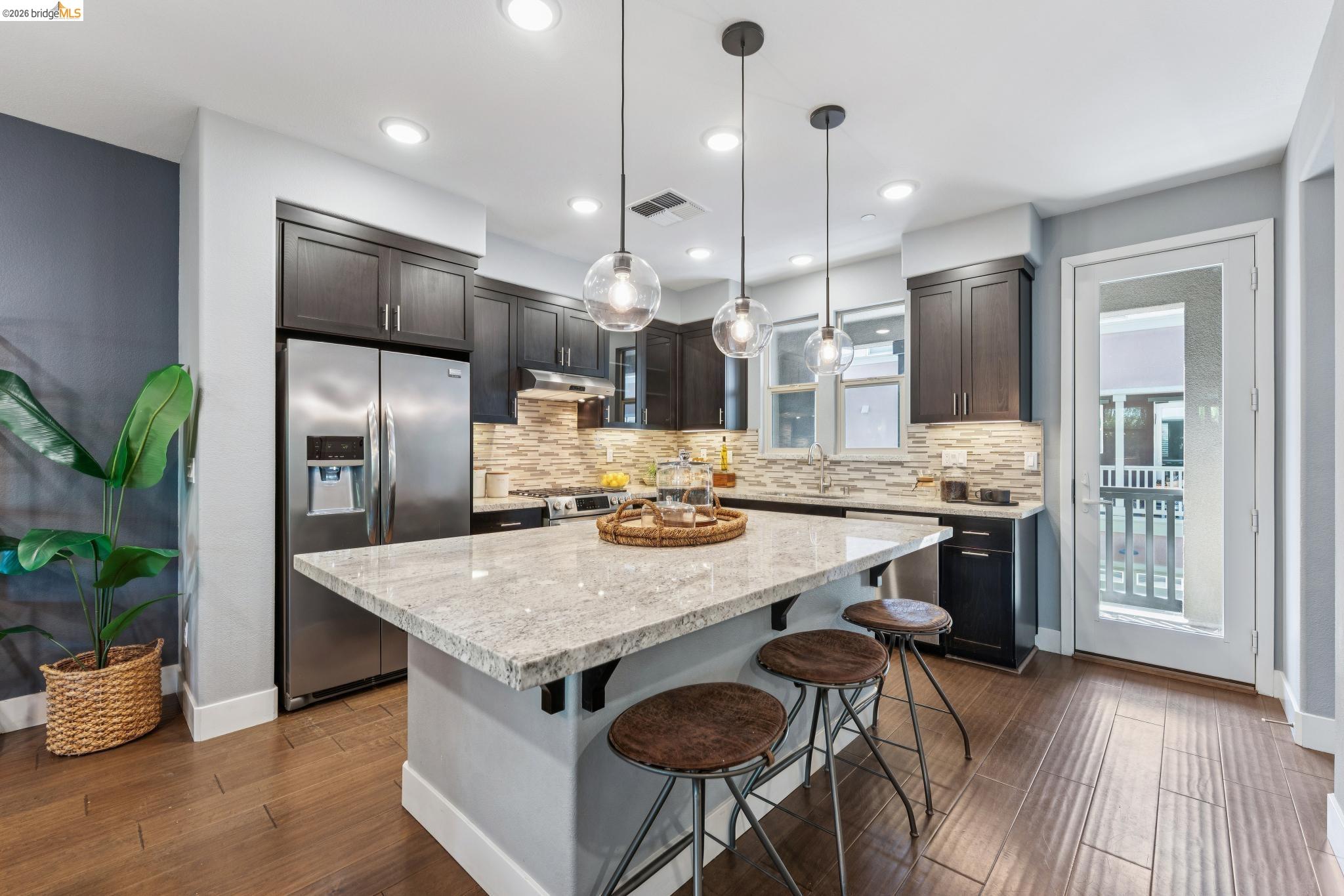 489 Diller Street Alameda, CA 94501 - Photo 15 of 60 Kitchen featuring dark wood-style flooring, stainless steel appliances, a breakfast bar, and light stone counters