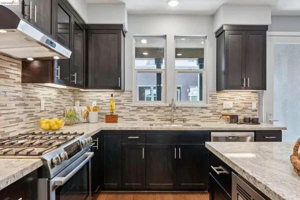 a kitchen with stainless steel appliances kitchen island granite countertop a stove a refrigerator a kitchen island a dining table and chairs with wooden floor